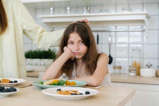 Young girl looking displeased with breakfast in a home kitchen setting.