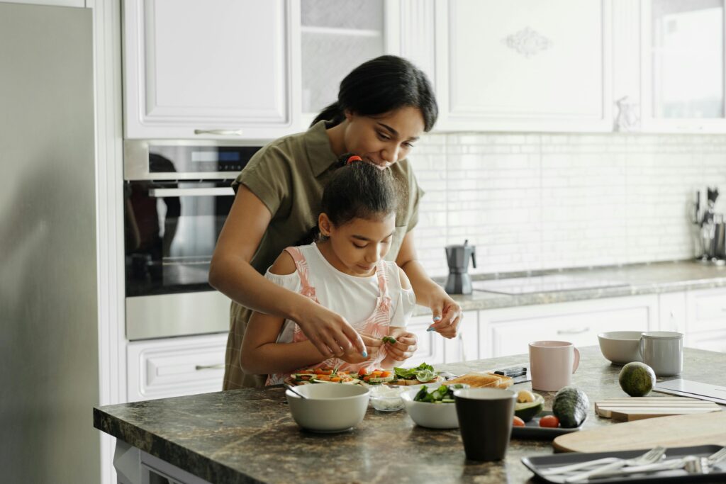 A mom and daughter share a bonding moment while preparing a healthy lunch together in the kitchen.