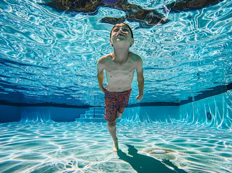 A joyful child swims underwater in a sunlit swimming pool, showcasing fun and skill.