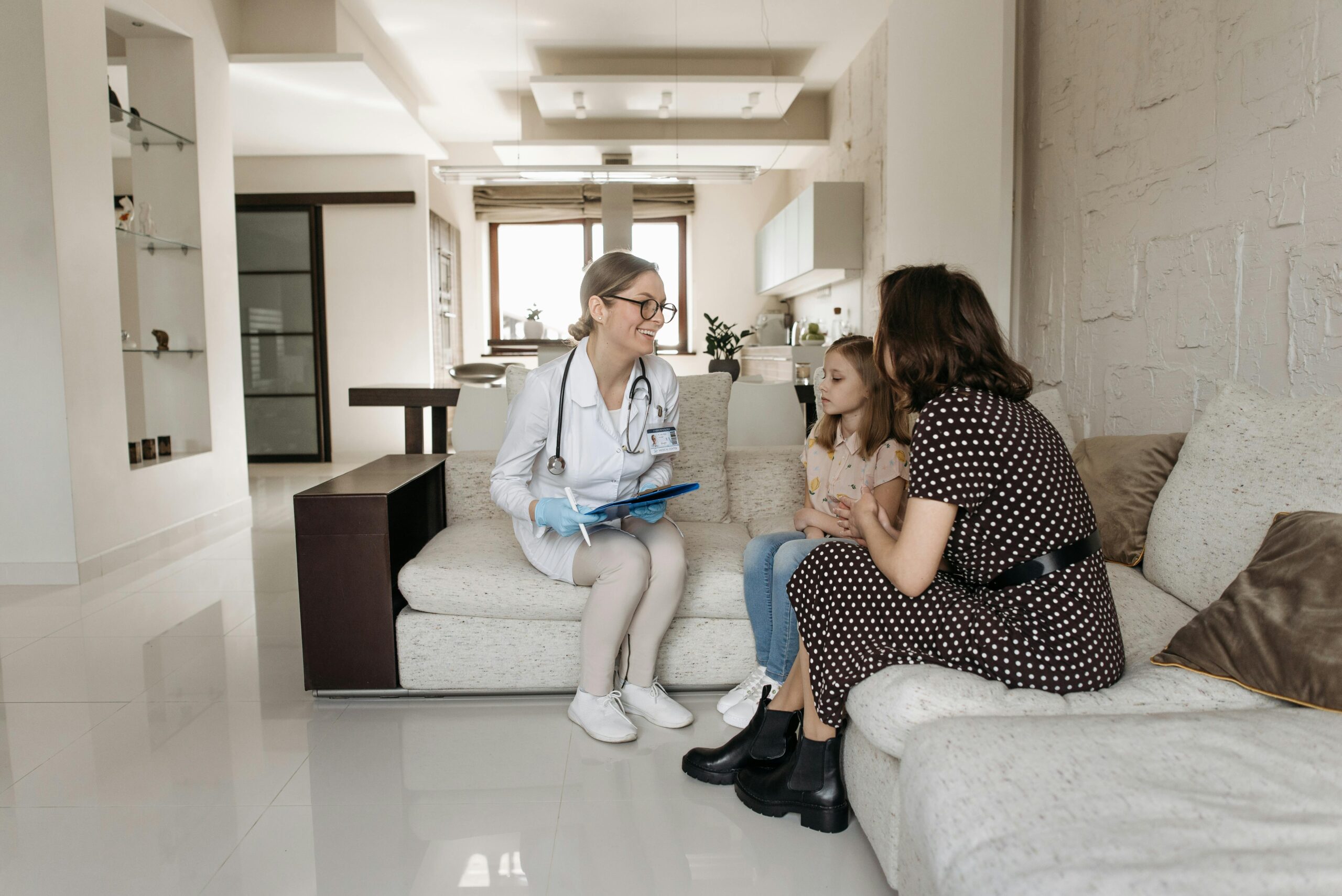 A mother and daughter receive a consultation from a female doctor at home.